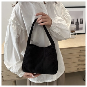 Detail of black corduroy tote bag showing soft ribbed texture and wide strap handle