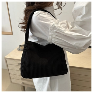 Close-up of black corduroy shoulder bag showing soft vertical knit texture and hobo shape