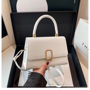 Detail of white leather handbag with golden square metal buckle and elegant top handle