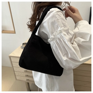 Detail of black corduroy shoulder bag with vertical stripe texture and minimalist design