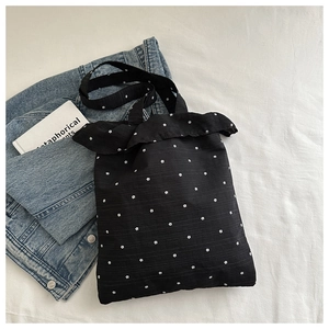 Detail of black floral tote bag with ruffle trim edge and white flower patterns