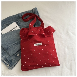 Detail of red floral chiffon tote bag featuring large ruffle trim and brand label