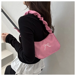 Close-up of pink ruffled shoulder strap and white bow embroidery on hobo bag