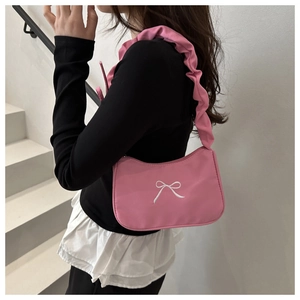 Detail of pink shoulder bag featuring white bow embroidery and ruffled strap design