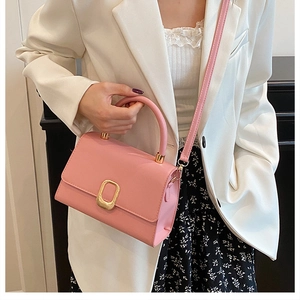 Detail of pink leather handbag featuring a square gold buckle and chic top handle
