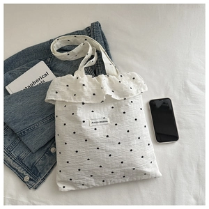 Close-up of white bubble texture chiffon tote bag with black flower embroidery and ruffle trim