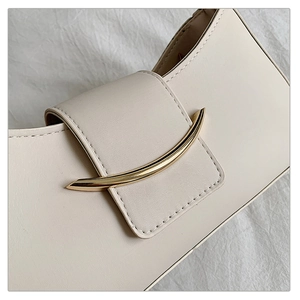 Detail of creamy white leather handbag featuring a stylish crescent-shaped gold metal buckle
