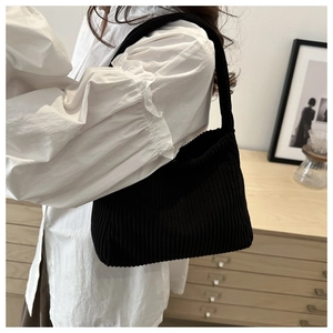 Close-up of black corduroy hobo shoulder bag styled with a white vintage blouse
