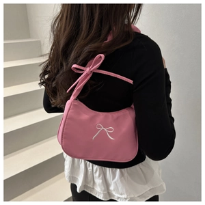 Close-up of pink shoulder bag featuring white bow embroidery and pleated texture design