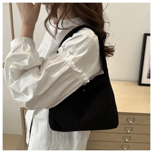 Detail of black corduroy tote bag showing fine ribbed texture and minimalist casual style