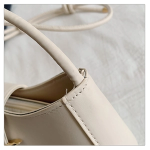 Detail of cream PU leather handbag showing strap stitching and connector craftsmanship