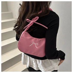 Detailed embroidery of white bow on pink shoulder bag in balletcore aesthetic style