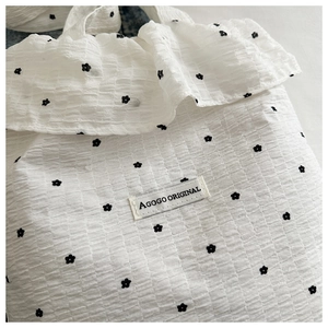 Detail of white seersucker tote bag with black floral print and ruffled edges