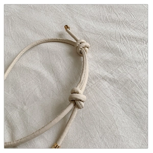 Detailed close-up of knotted cream leather straps with elegant gold metallic caps