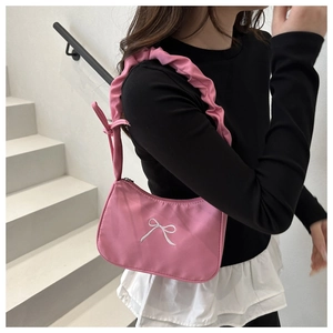 Close-up of pink nylon underarm bag featuring white bow embroidery and ruched strap details
