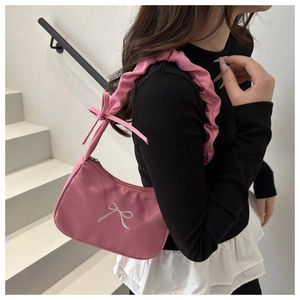 Close-up of pink pleated shoulder bag featuring white bow embroidery and ribbon details