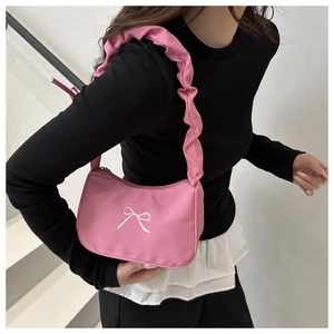 Detail of pink nylon shoulder bag featuring white embroidered bow and ruched cloud strap