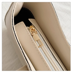 Macro shot of smooth gold zipper detail and pebble leather texture on small square bag