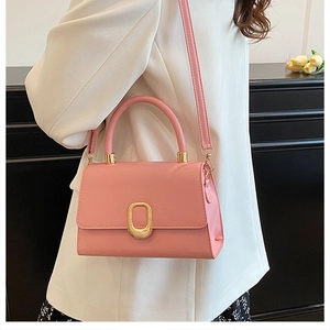 Detail of pink PU leather crossbody bag with gold oval clasp on white blazer