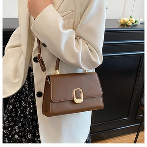 Close-up of a brown leather crossbody square bag with a vintage gold metal buckle