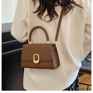 Close-up of brown faux leather handbag with elegant gold oval lock and textured matte finish