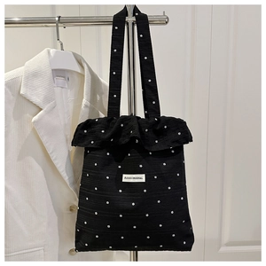 Detail of floral tote bag with ruffle trim and branded label against a minimal background