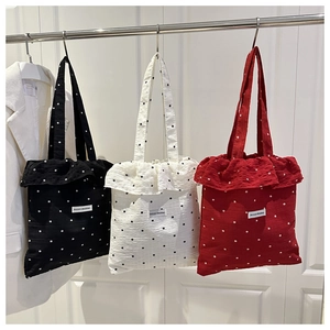 Detail of ruffled mesh tote bags in black white and red with floral patterns