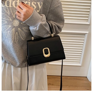 Detail of minimalist black leather crossbody bag with elegant gold metal buckle closure