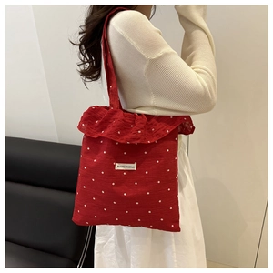 Detail of red floral tote bag with ruffle trim and AGOGO ORIGINAL woven label on strap