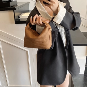 Sac hobo marron tressé au design minimaliste porté par un mannequin en tenue chic