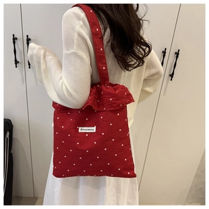 Detail of red floral tote bag with ruffle trim and white embroidered flower pattern