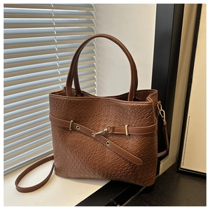 Gros plan sur la texture du cuir tressé marron avec boucle décorative et détails métal
