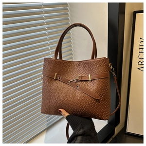 Détail d'un sac cabas marron à motif crocodile avec sangle décorative et boucle métal