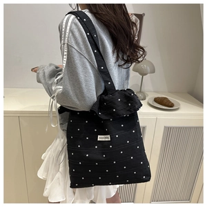 Detail of black floral canvas tote bag with white flower patterns and woven brand label