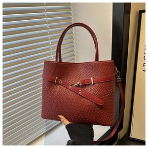 Détail d'un sac à main rouge texturé crocodile avec poignées robustes et bride à boucle