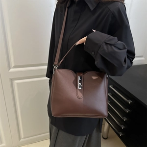Retro dark brown bucket bag with metallic silver buckle worn on a shoulder strap