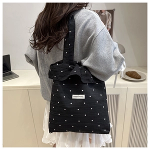 Detail of black ruffled tote bag with white floral pattern and branded AGOGO woven label