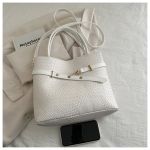Détails de la texture tissée et du fermoir doré sur un grand sac cabas blanc épuré