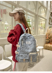 Détail d'un sac à dos gris clair à motif marbré avec boucles et poches extérieures