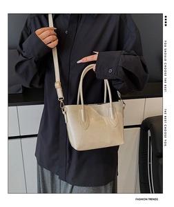 Close-up of beige minimalist tote bag with smooth matte leather and gold hardware detail