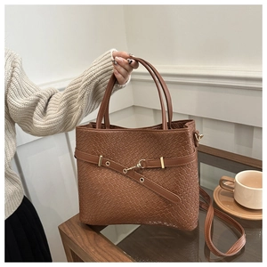 Détail d'un sac cabas marron tressé avec fermoir rotatif et bandoulière amovible