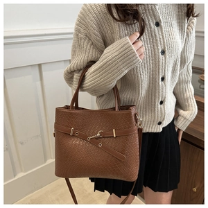 Gros plan d'un sac seau marron tressé avec boucle dorée et bandoulière amovible
