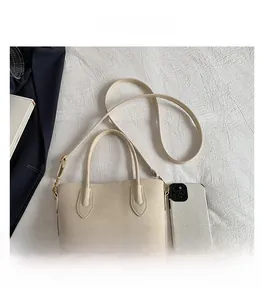 Detail view of large beige tote bag compared with a smartphone for size reference