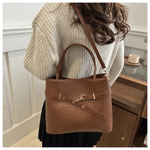 Gros plan d'un sac cabas marron à texture tressée avec boucle en métal et sangle