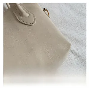 Detail of light beige textured leather tote with gold hardware and fine stitching