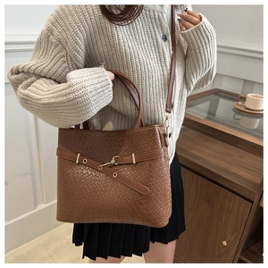 Détail du sac à main marron tissé avec sangle décorative et finitions dorées chic