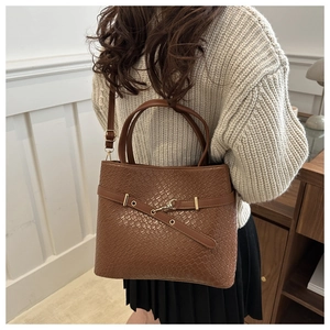 Détail d'un sac cabas marron tissé avec bandoulière réglable et finitions dorées