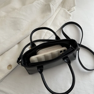 Classic black square handbag with top handles and shoulder strap showing daily capacity
