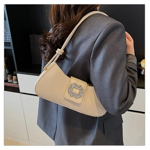 Détail du sac à main crème avec boucle carrée en cristal porté sur une veste grise