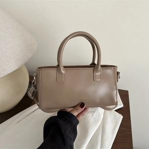 Retro khaki small square handbag with fashion embossing on a minimal wooden desk